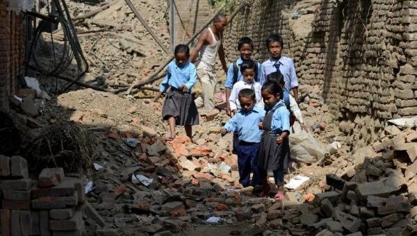 Nepalese students walks to school past buildings damaged in devastating earthquakes, in Bhaktapur on the outskirts of Kathmandu on May 31, 2015.