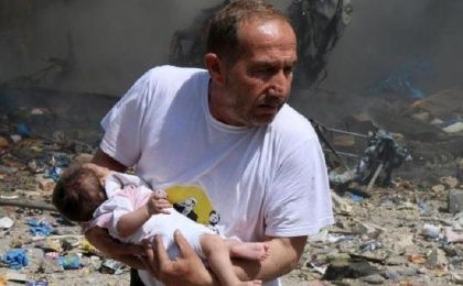 A man holds a baby that survived what activists said was a site hit by a barrel bomb dropped by forces loyal to Syrian President Bashar al-Assad at the old city of Aleppo June 3, 2015.