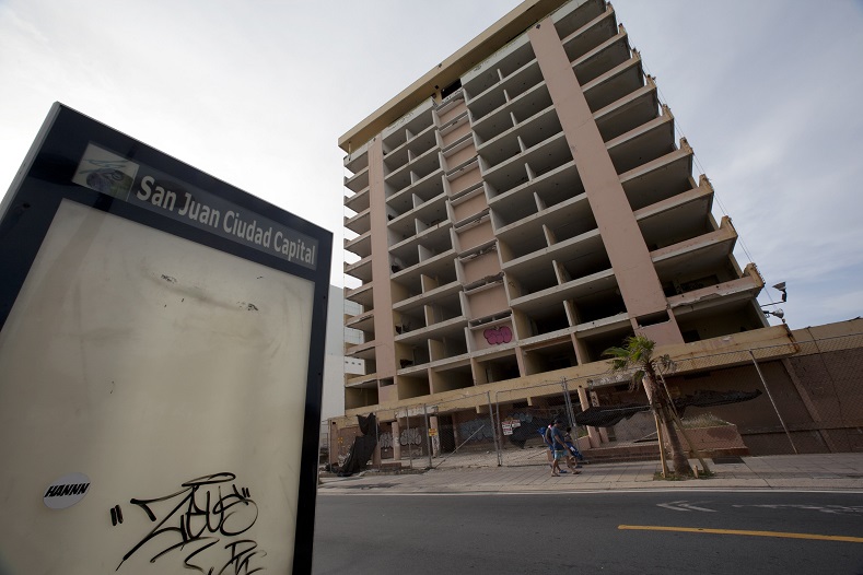Pedestrians pass an abandoned hotel in the tourist area of San Juan, Puerto Rico, July 18, 2015.