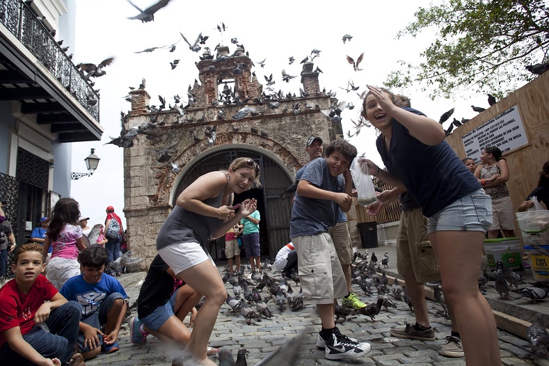 Tourists react to a flock of pigeons as they visit Parque de las Palomas in San Juan, Puerto Rico, July 18, 2015. While other Caribbean islands have witnessed a steady growth of tourism, the debt crisis in Puerto Rico has contributed to the stagnated tourism industry.