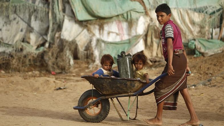 A boy pushes a wheel cart with two children and a jerrycan as they head to collect water from a tap at a camp for internally displaced persons (IDPs) in al-Mazraq in the northwestern Yemeni province of Hajja May 20, 2013.