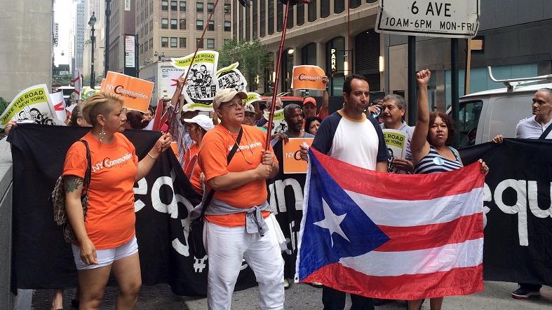 Protesters march while holding the flag of Puerto Rico during a demonstration against proposed austerity measures along Park Avenue offices of a major holder of Puerto Rico’s debt in New York in July 30, 2015.