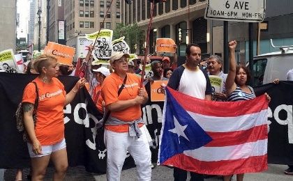 Protesters march while holding the flag of Puerto Rico during a demonstration against proposed austerity measures along Park Avenue offices of a major holder of Puerto Rico’s debt in New York in July 30, 2015. 