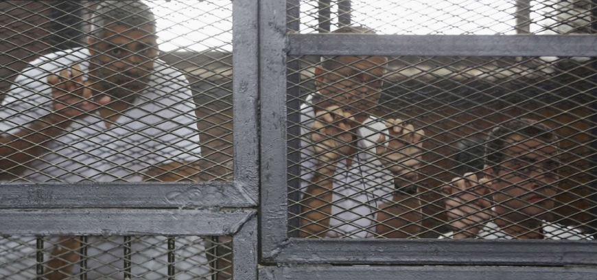 Al Jazeera journalists from left Mohamed Fahmy, Peter Greste and Baher Mohamed stand behind bars at a court in Cairo in 2014, before they were released on bail in February.