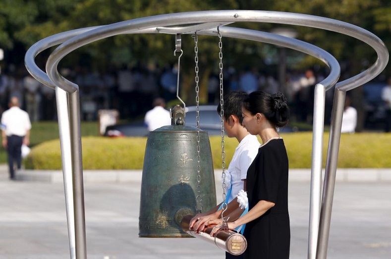 People ring a bell to mark the moment when an atom bomb exploded over Hiroshima 70 years ago during a commemoration ceremony at Peace Memorial Park in Hiroshima, August 6, 2015.