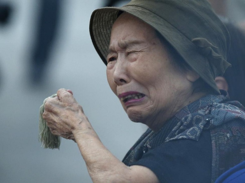 A woman reacts as she prays for the atomic bomb victims in front of the cenotaph for the victims of the 1945 atomic bombing, at Peace Memorial Park in Hiroshima, August 6, 2015.