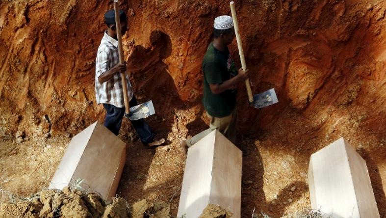 Workmen walk among coffins in a mass grave of unidentified Rohingya remains found at a traffickers camp in Malaysia.