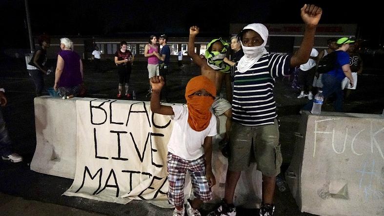 Three young protesters join the demonstration outside the police department in Ferguson, Missouri August 7, 2015.