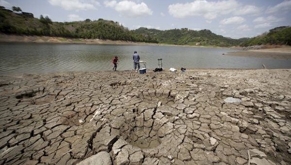A man and a boy try to fish while standing on the dry shores of the almost empty La Plata reservoir in Toa Alta, Puerto Rico.