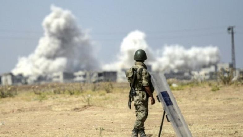 A view from the Turkish side of the border in Suruc, Sanliurfa province, shows a solider standing as smoke rises from the Syrian town of Kobane on June 27, 2015, a day after a deadly suicide bombing occurred.