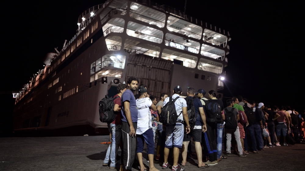 A group of migrants wait to embark a liner, which will serve as a registration and accommodation centre at the island of Kos