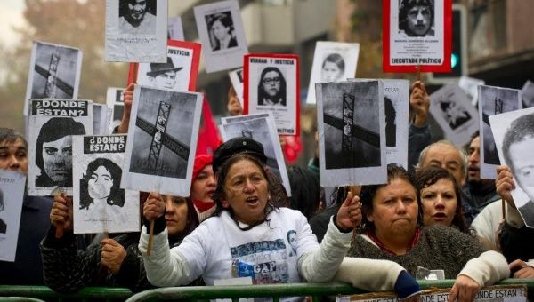 Demonstrators holding posters with the portraits of missing or killed relatives protest in Santiago, Chile.