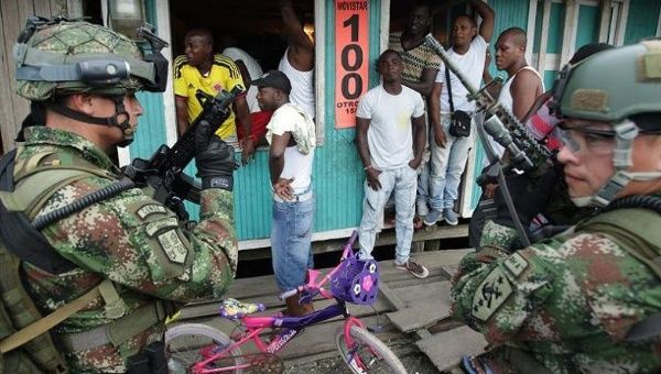 Soldiers guard an official's visit to a neighborhood in Colombia. Human rights defenders have called for the military to be investigated for human rights abuses.