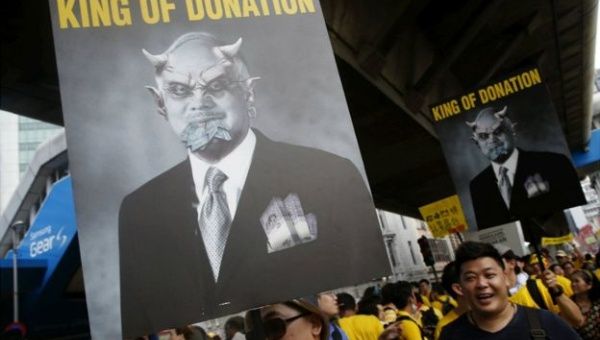 Malaysian protesters hold derogatory signs of Prime Minister Najib Razak.