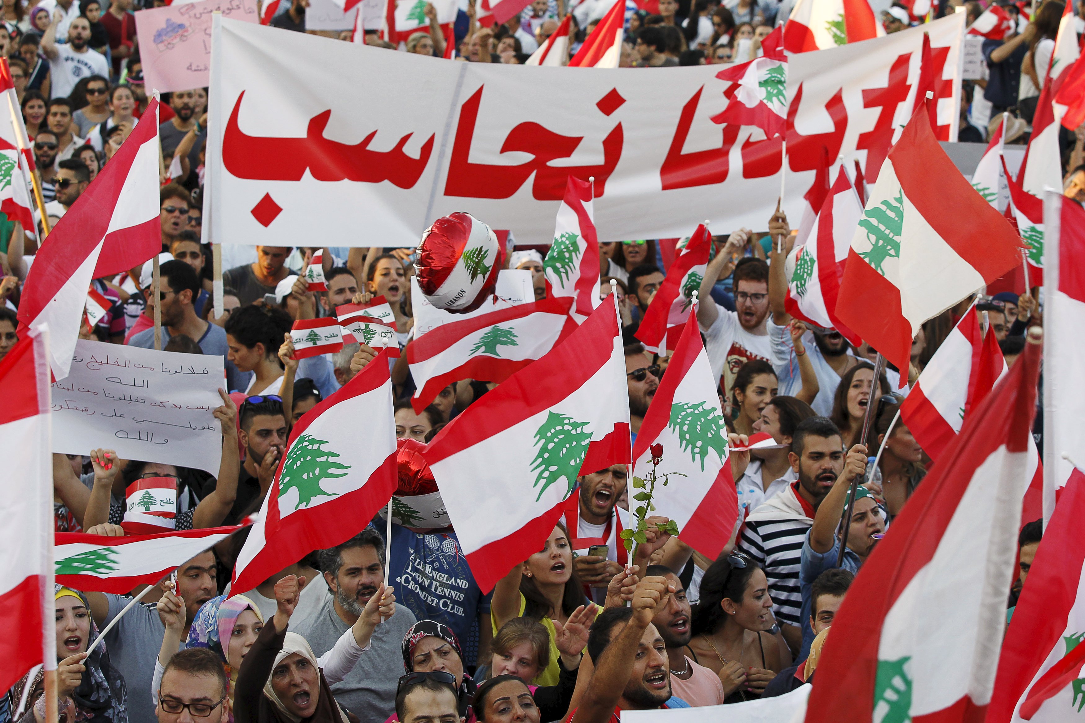 People carry Lebanese national flags and banners as they take part in an anti-government protest at Martyrs' Square in downtown Beirut, Lebanon August 29, 2015.