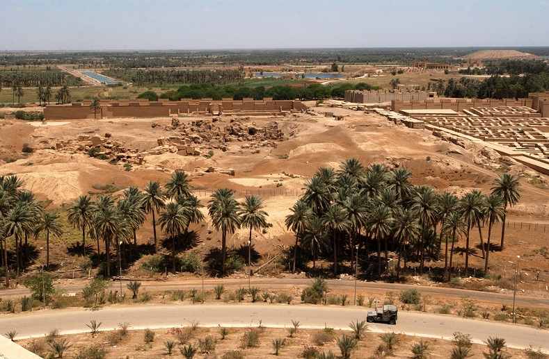 Marine Corps Humvee vehicle drives down a road at the foot of Saddam Hussein's former Summer palace with ruins of ancient Babylon in the background, Iraq. Simon Jenkins, writing in The Guardian in 2007, details how the U.S. troops destroyed much of Babylon, saying the