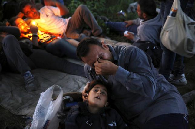 Kurdish Syrian refugee Sahin Serko cries next to his 7-year-old daughter Ariana minutes after crossing the border into Macedonia, along with another 45 Syrian refugees, near the Greek village of Idomeni in Kilkis prefecture May 14, 2015.