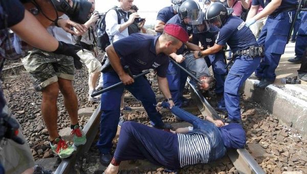 Hungarian policemen detain Syrian refugees on the tracks as they wanted to run away at the railway station in the town of Bicske, Hungary, September 3, 2015.