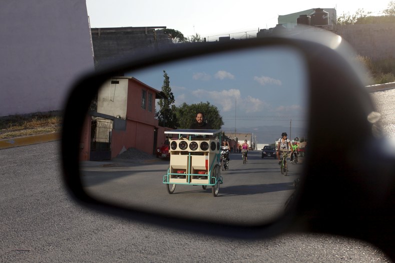 Reginaldo Chapa is reflected in a side mirror as he pedals his Cinecleta, Moviebike, through the streets of Saltillo, Mexico, Sept. 6, 2015.