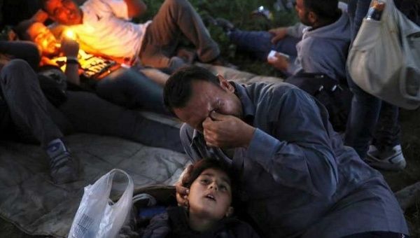 Kurdish Syrian refugee Sahin Serko cries next to his 7 year-old daughter Ariana minutes after crossing the border into Macedonia, along with another 45 Syrian immigrants, near the Greek village of Idomeni in Kilkis prefecture May 14, 2015.