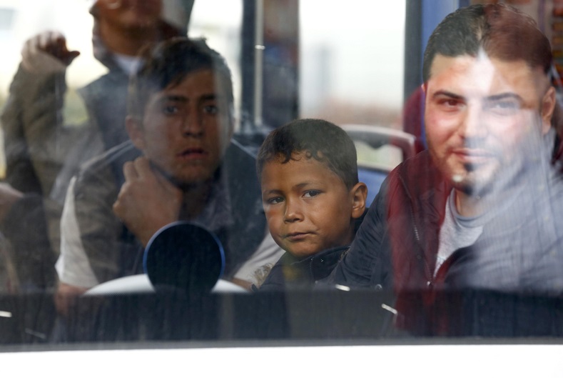 Refugees look through the window of a train at the main station in Munich, Germany, September 5, 2015.