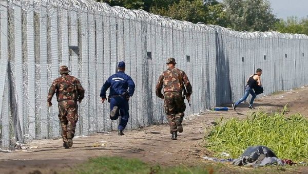 Officers chase a migrant who crossed into Hungary on Saturday