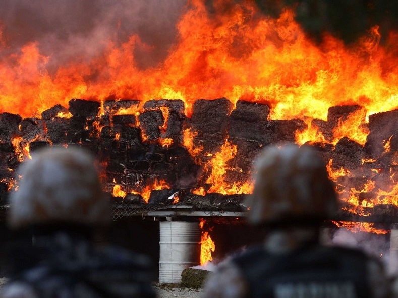 Police officers observe as tons of drugs are incinerated in Tijuana, Mexico, a city with a 30 per 100,000 murder rate.