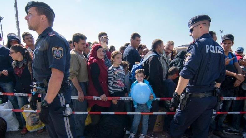 Austrian security forces stand in front of migrants waiting at the Hungarian-Austrian border near Nickelsdorf, on Sept. 12, 2015.