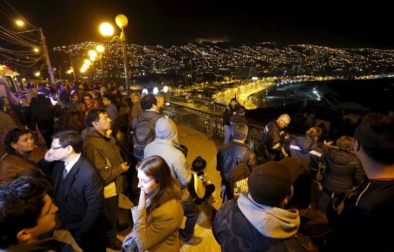 People stand and watch the ocean on Cerro Baron hill, in Valparaiso city, after a mass evacuation of the entire coastline during a tsunami alert, September 16, 2015.