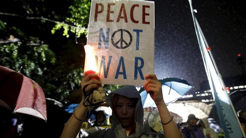 A protester holding a placard takes part in a rally against Japan's Prime Minister Shinzo Abe's security bill and his administration in front of the parliament in Tokyo, Japan, September 17, 2015.