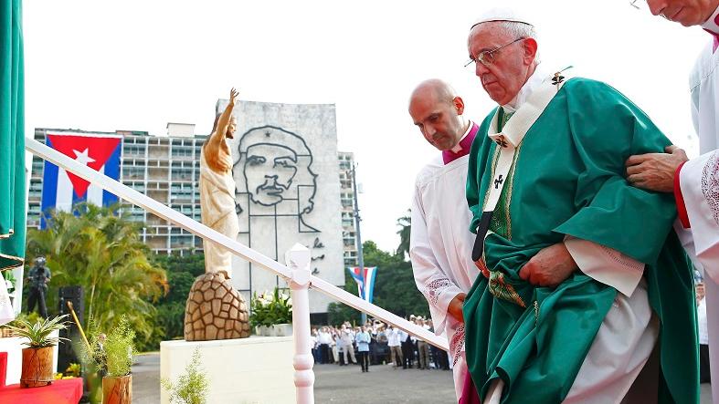Pope Francis climbs the steps to the altar to give the first mass of his visit to Cuba in Havana, a portrait of Che Guevara on the front of the Interior Ministry building can be seen in the background, September 20, 2015.