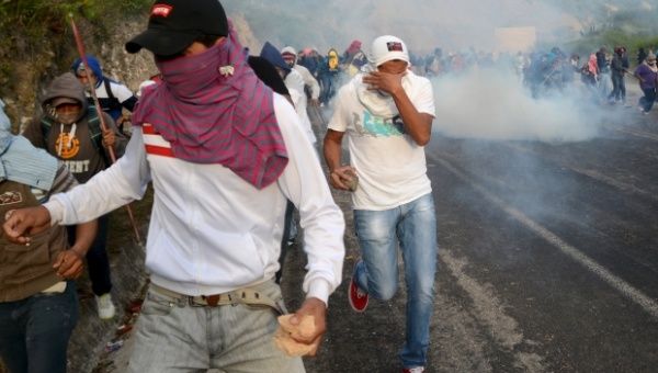 Protesters run away from tear gas during confrontations with riot police on the highway outside of Guerrero, Mexico Sept. 22, 2014. 
