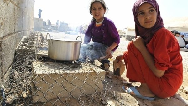 Two Syrian refugee girls cook in a refugee camp near the border with Jordan