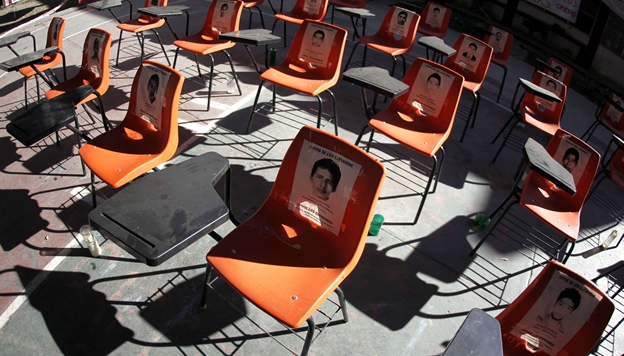 Activists place desks with the pictures of the 43 missing students as a symbolic demonstration
