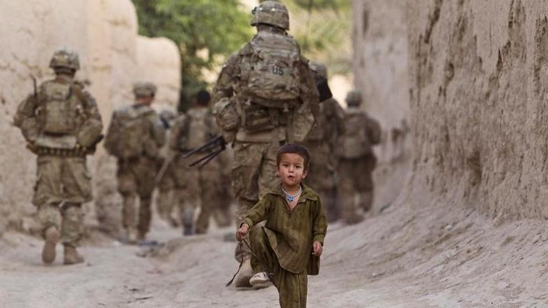 A boy plays on a street as U.S. Army soldiers of the Battle company patrol during a mission in Zahri district of Kandahar province, southern Afghanistan May 30, 2012.