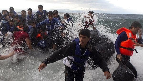 Refugees and migrants struggle to jump off an overcrowded dinghy on the Greek island of Lesbos, after crossing in rough seas from the Turkish coast.