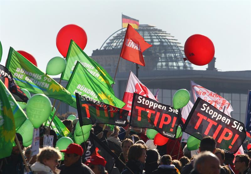 Protesters carry banners and balloons during a rally against the trade agreements TTIP and CETA near the German 'Reichstag' building in Berlin, Germany, 10 Oct. 2015.
