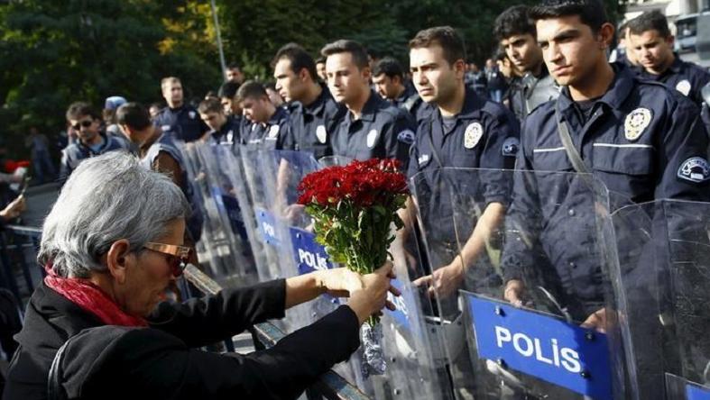 A demonstrator holds flowers before a police barricade during a commemoration for the victims of Saturday's bomb blasts in the Turkish capital, in Ankara, Turkey, October 11, 2015.
