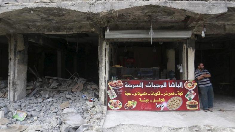 A vendor stands near his fast food shop amid rubble in Aleppo, Syria Oct. 13, 2015.
