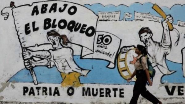 A pedestrian walks past graffiti in Cuba that reads 