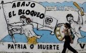 A pedestrian walks past graffiti in Cuba that reads "Down with the blockade."