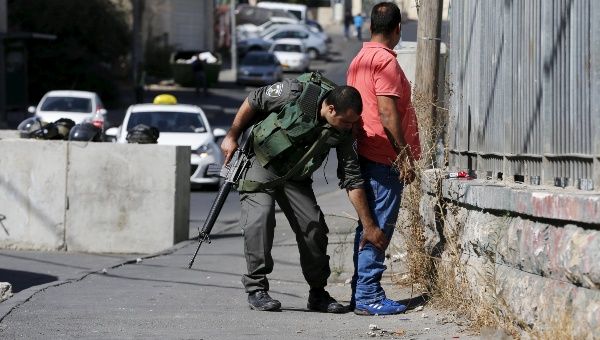 An Israeli border policeman checks a Palestinian man at a new roadblock in East Jerusalem October 15, 2015. 
