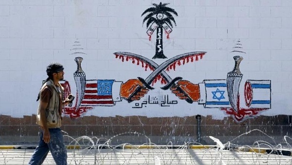 A Yemeni man walks past anti-Saudi and US graffiti sprayed on the wall of the vacant Saudi embassy.