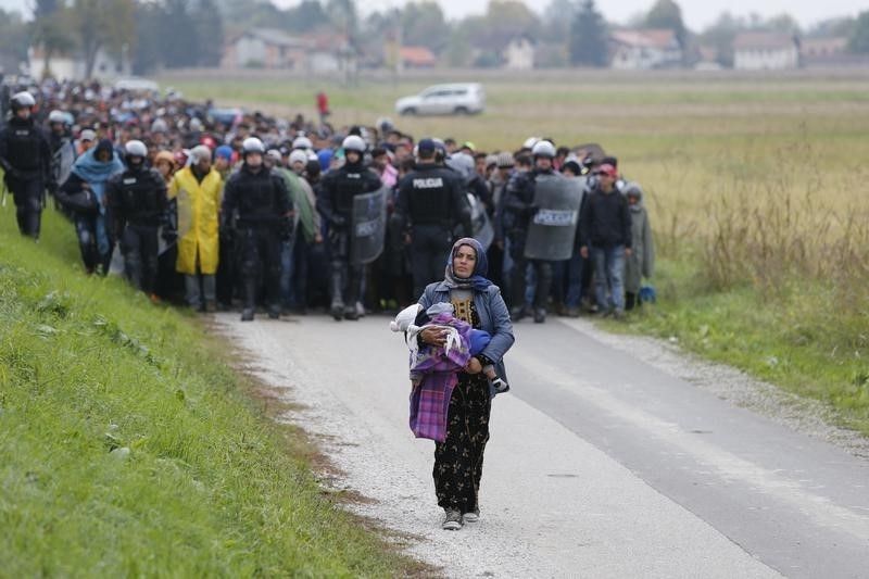 Police officers escort Fatima from Syria (front) and other migrants as they make their way on foot after crossing the Croatian-Slovenian border.