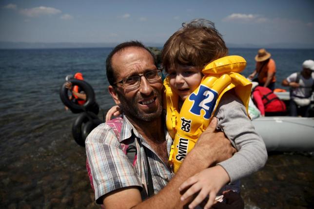 Syrian refugee Mustafa Mohammad embraces a boy after arriving on a dinghy at the Greek island of Lesbos, Aug. 6, 2015.