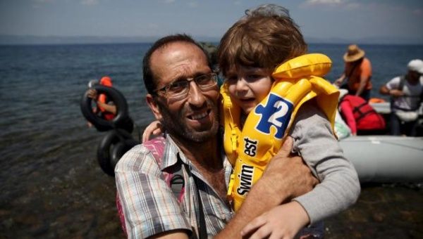 Syrian refugee Mustafa Mohammad embraces a boy after arriving on a dinghy at the Greek island of Lesbos, Aug. 6, 2015. 