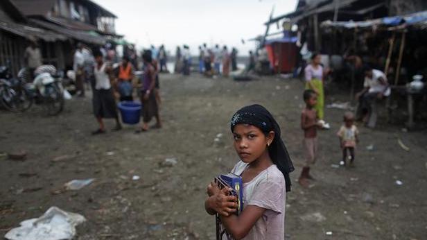 A Myanmar Rohingya girl carries her books through a fish market on her way to school in the town of Sittwe, May 19, 2012.