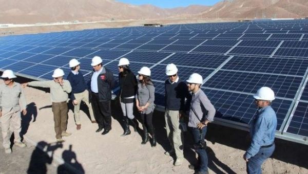 Project developers look at solar panels in Chile's Atacama desert. 