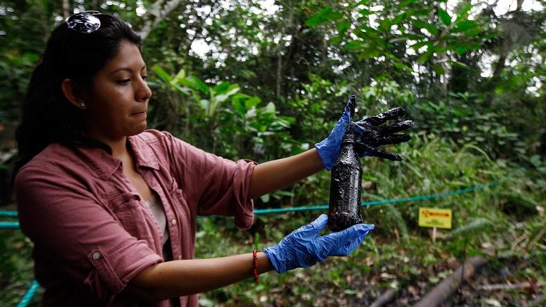 Environmental activist Cyntia Zapata shows a plastic bottle with some oil waste from a pool of waste that Chevron left behind in the fields they operated in the Amazon, Ecuador, Sep. 17, 2013.