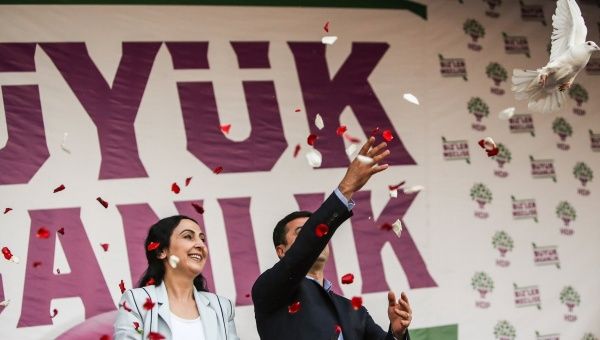 Figen Yüksekdağ and Selahattin Demirtaş address a crowd of supporters with a huge banner behind them saying 